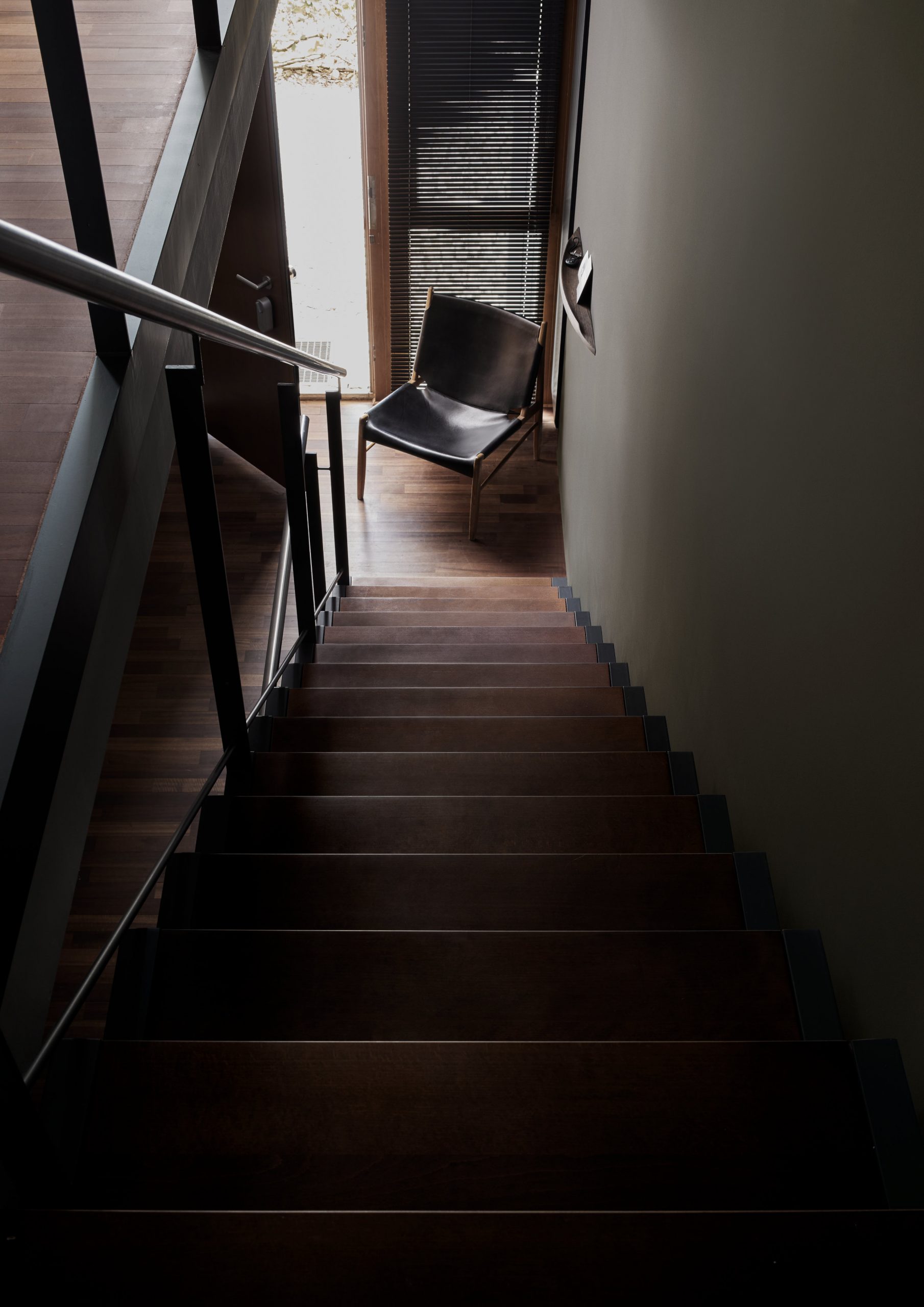 PEAM Haus S. Blick von der Treppe nach unten, Nussbaumholz, schwarzer Ledersessel Vintage, dunkelgraue Wand