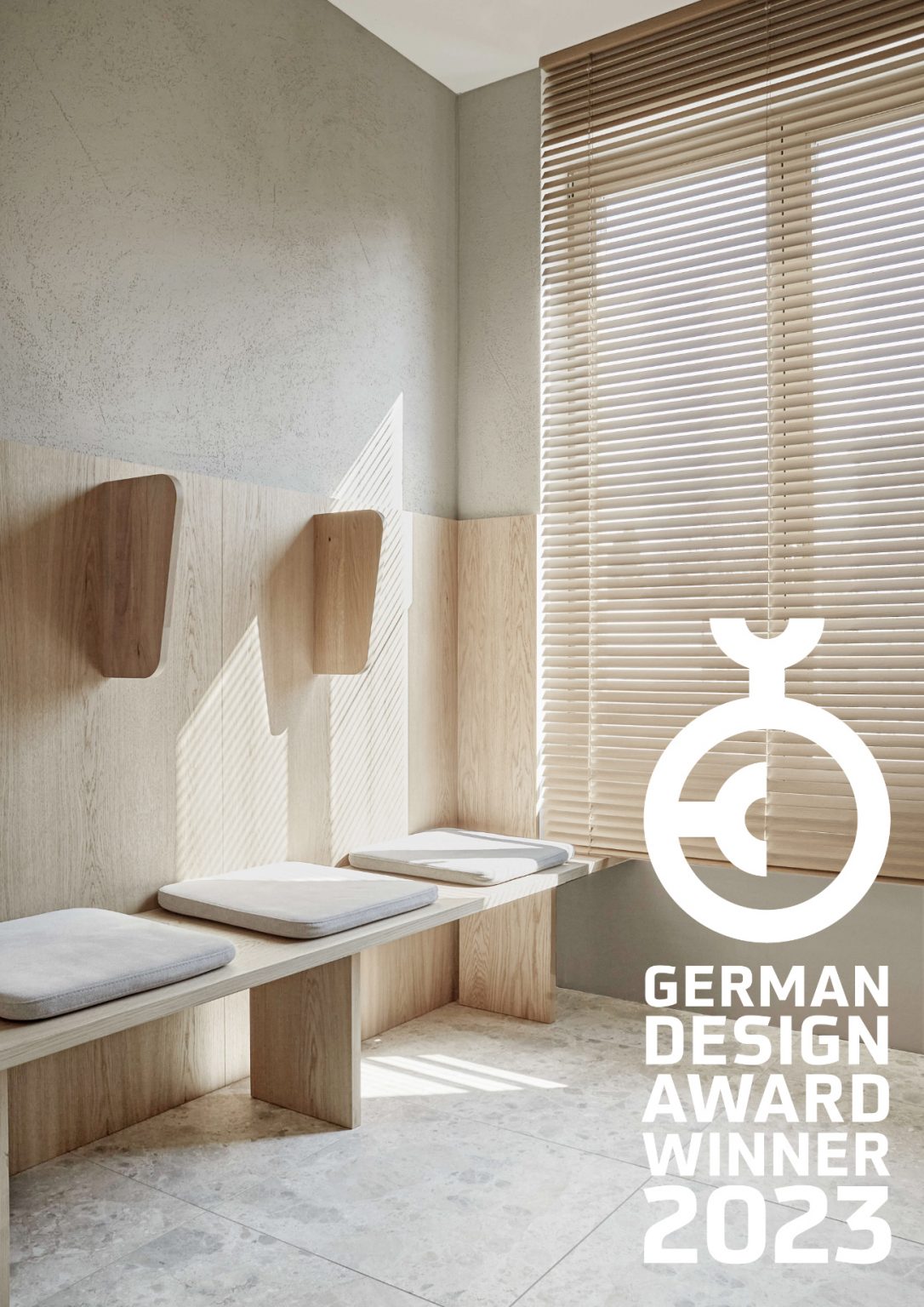 Lichtdurchfluteter Wartebereich mit Sitzbank aus Eichenholz, minimalistischen Wandhaken und textilen Sitzkissen, kombiniert mit Natursteinboden und Holzjalousien im modernen Praxisdesign.